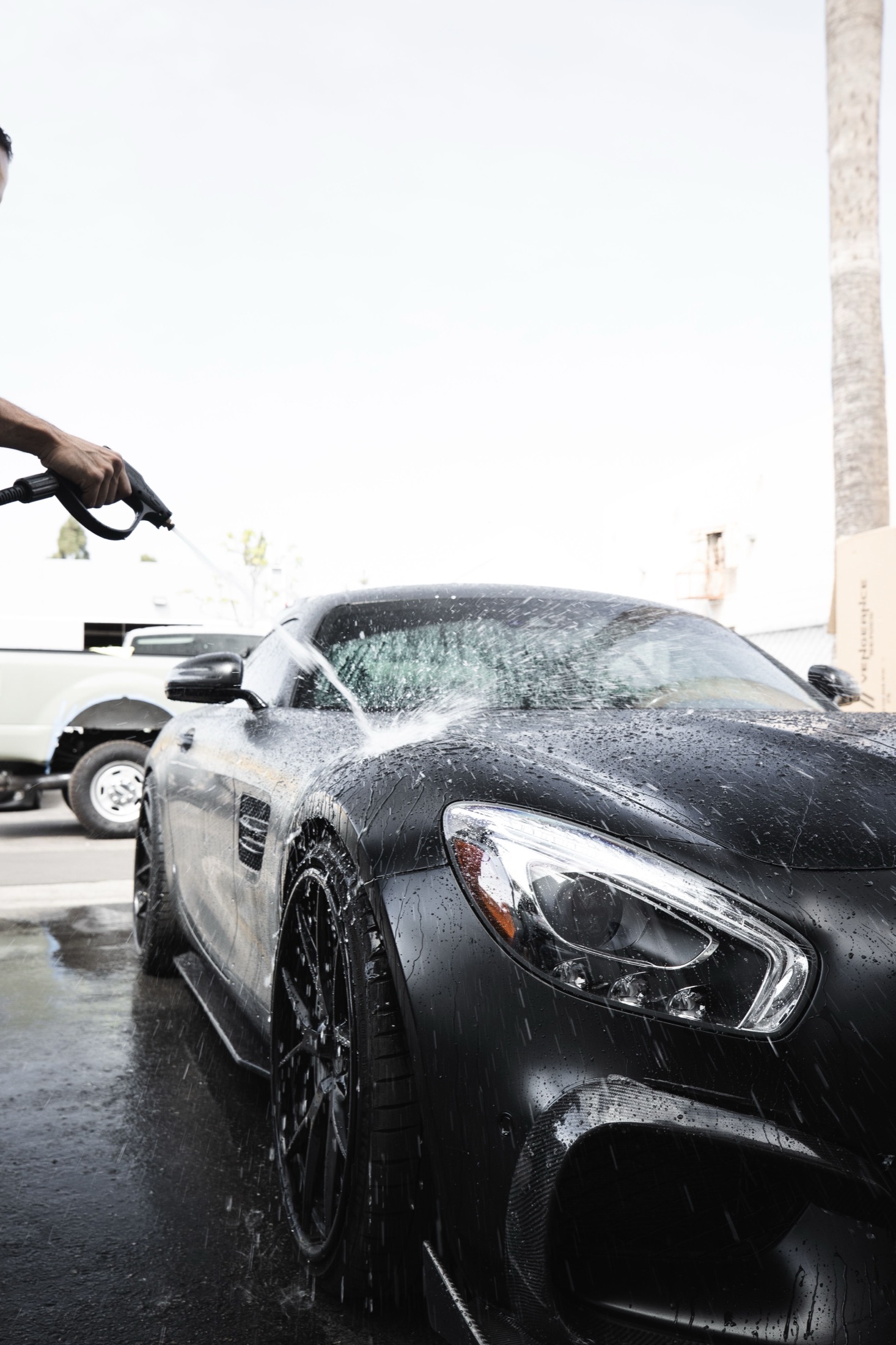 A black vehicle being washed with a pressure hose