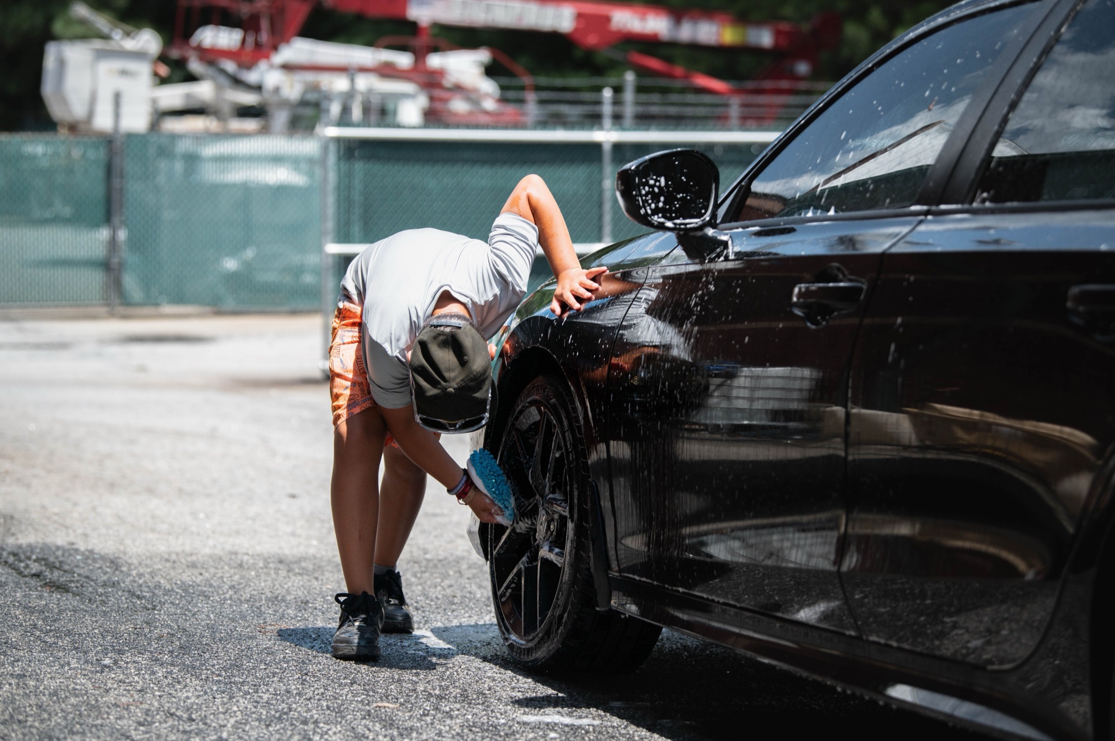 A black vehicle wheel being cleaned outdoors